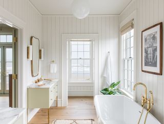 bathroom with seaview, white panelling, freestanding bath, pale green vanity and wooden floor