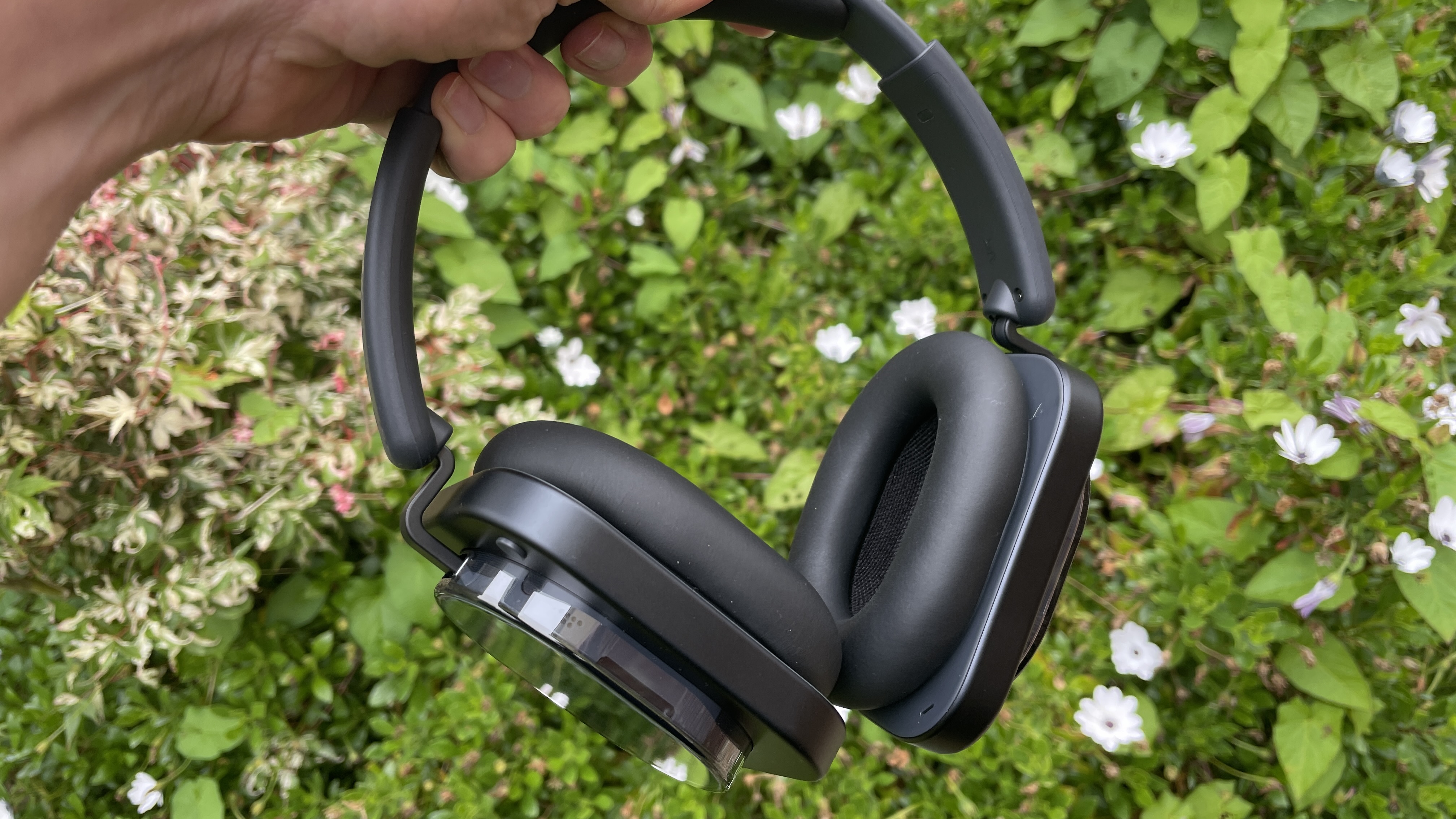 Nothing Headphone (1) in black, on a pink rose and floral background, held in a woman's hand