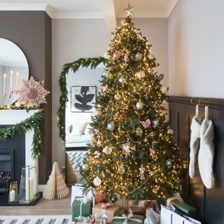 A living room with a fireplace and a Christmas tree decorated with vintage-style ornaments