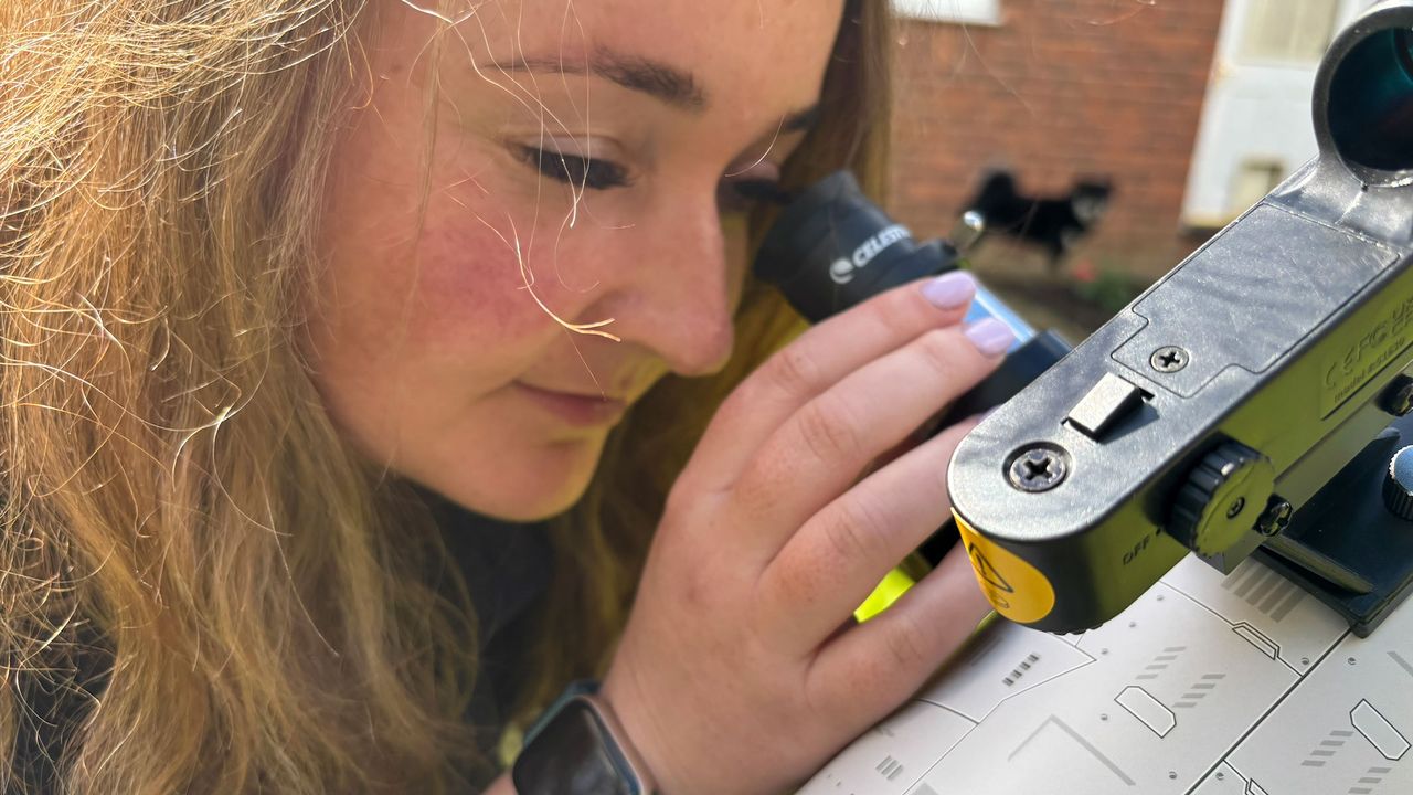 A woman looking through the eyepice of the Celestron Moon Mission 100mm Tabletop Dobsonian.