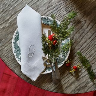 white Christmas napkin with letter G folded and placed neatly on green and white side plate