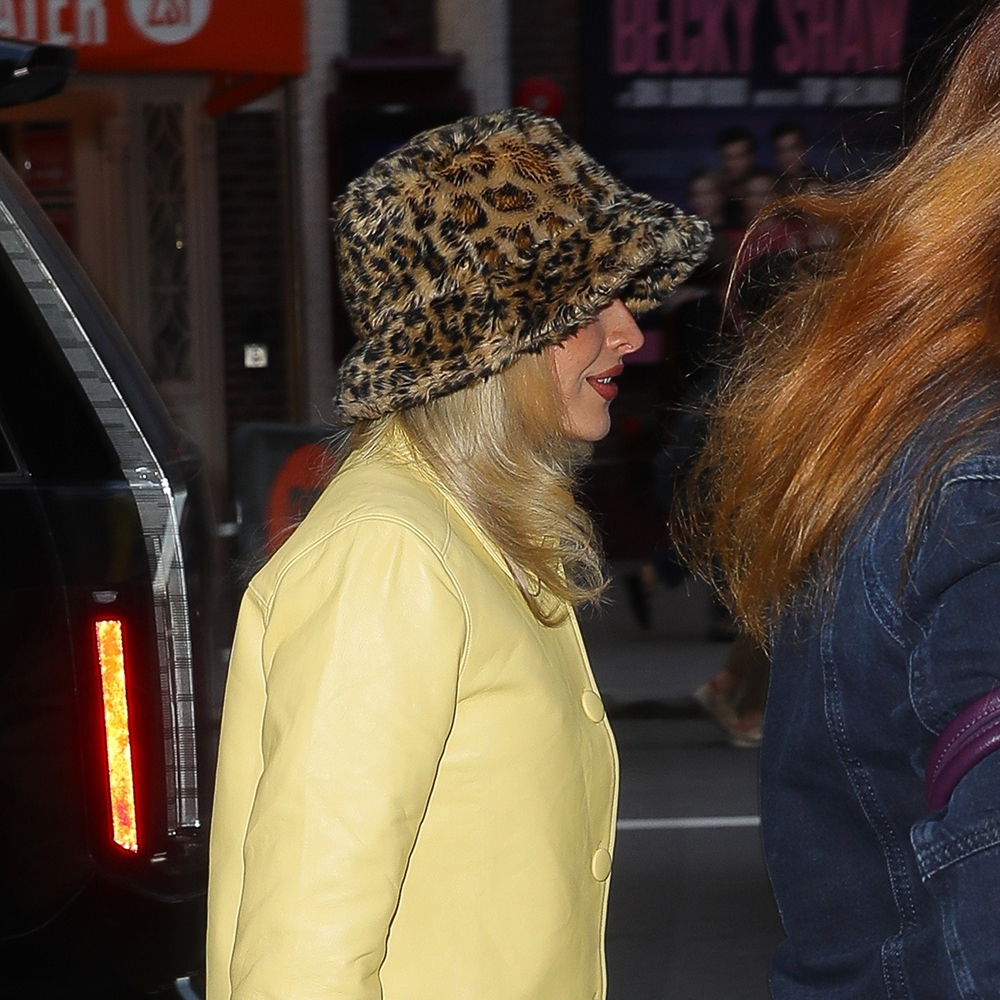 Sabrina Carpenter wearing a yellow leather jacket, baggy blue jeans, and open toe heels 