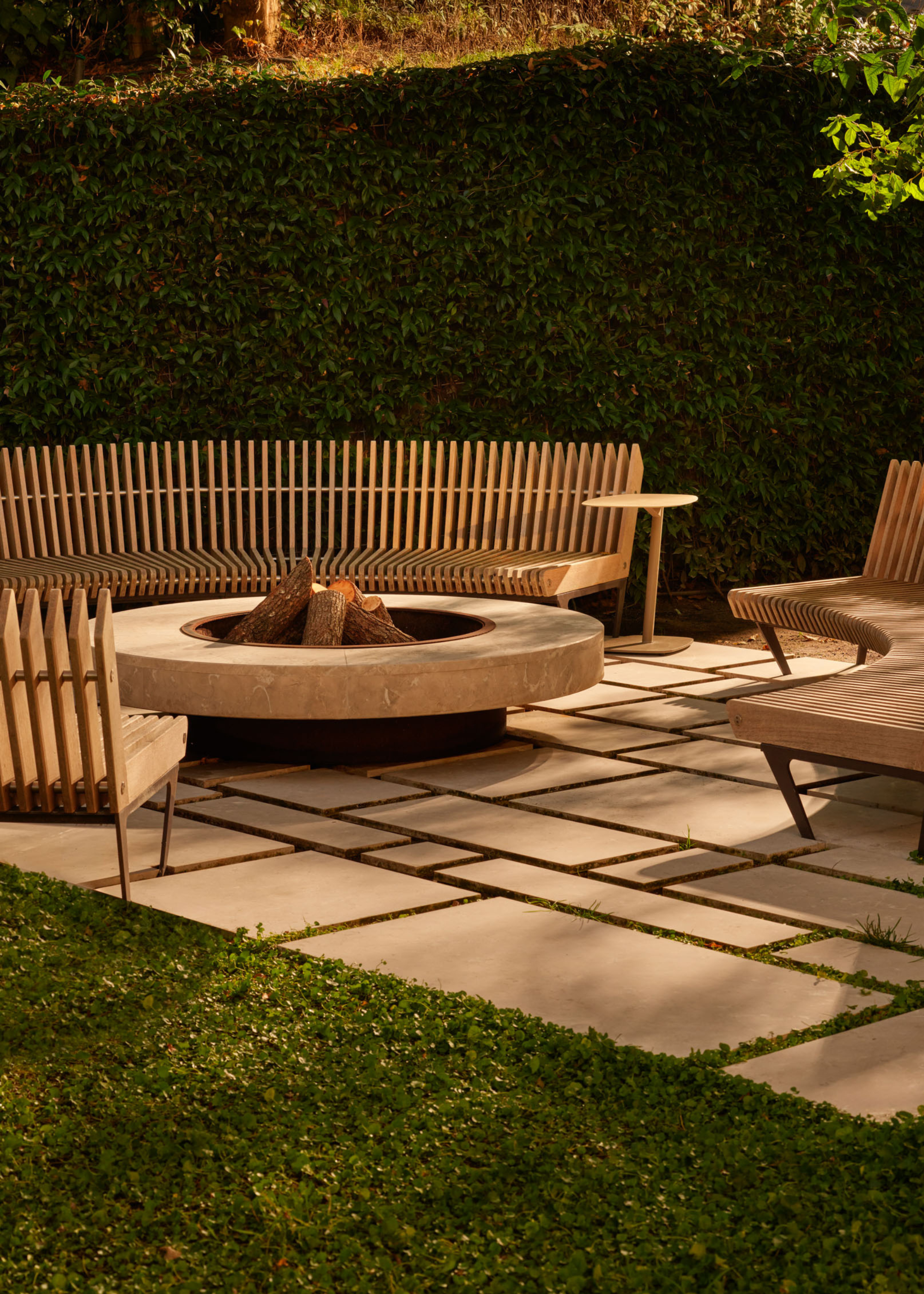 An outdoor garden with a fire pit and round wood benches