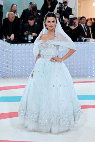 Penelope Cruz arrives on the Met Gala 2023 red carpet wearing a bridal inspired white and silver sequin Chanel dress with stunning veil