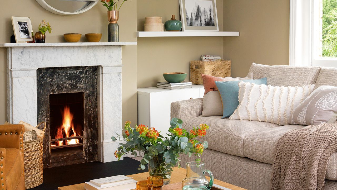 Beige living room with white marble fireplace, open fire and a cream sofa lined with neutral cushions