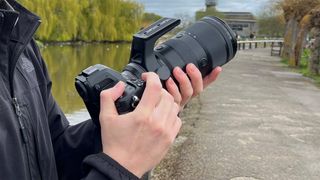 Mike Harris holding Nikon Z 70-200mm f/2.8 VR S II by a lake with vegetation and trees in the background