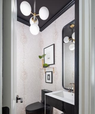 A bathroom with cream patterned wallpaper and a black ceiling and woodwork