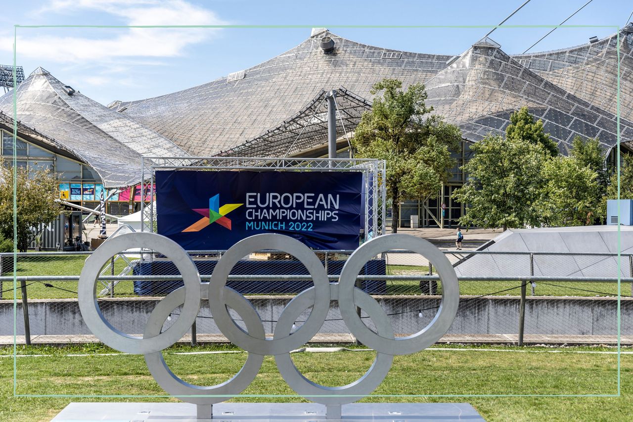 A sign reading &#039;European Championships Munich 2022&#039; behind a statue of the Olympic rings