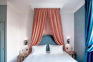 A bright bedroom with a pink curtain canopy over the bed