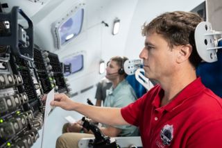 two people in the cockpit of a spacecraft simulator