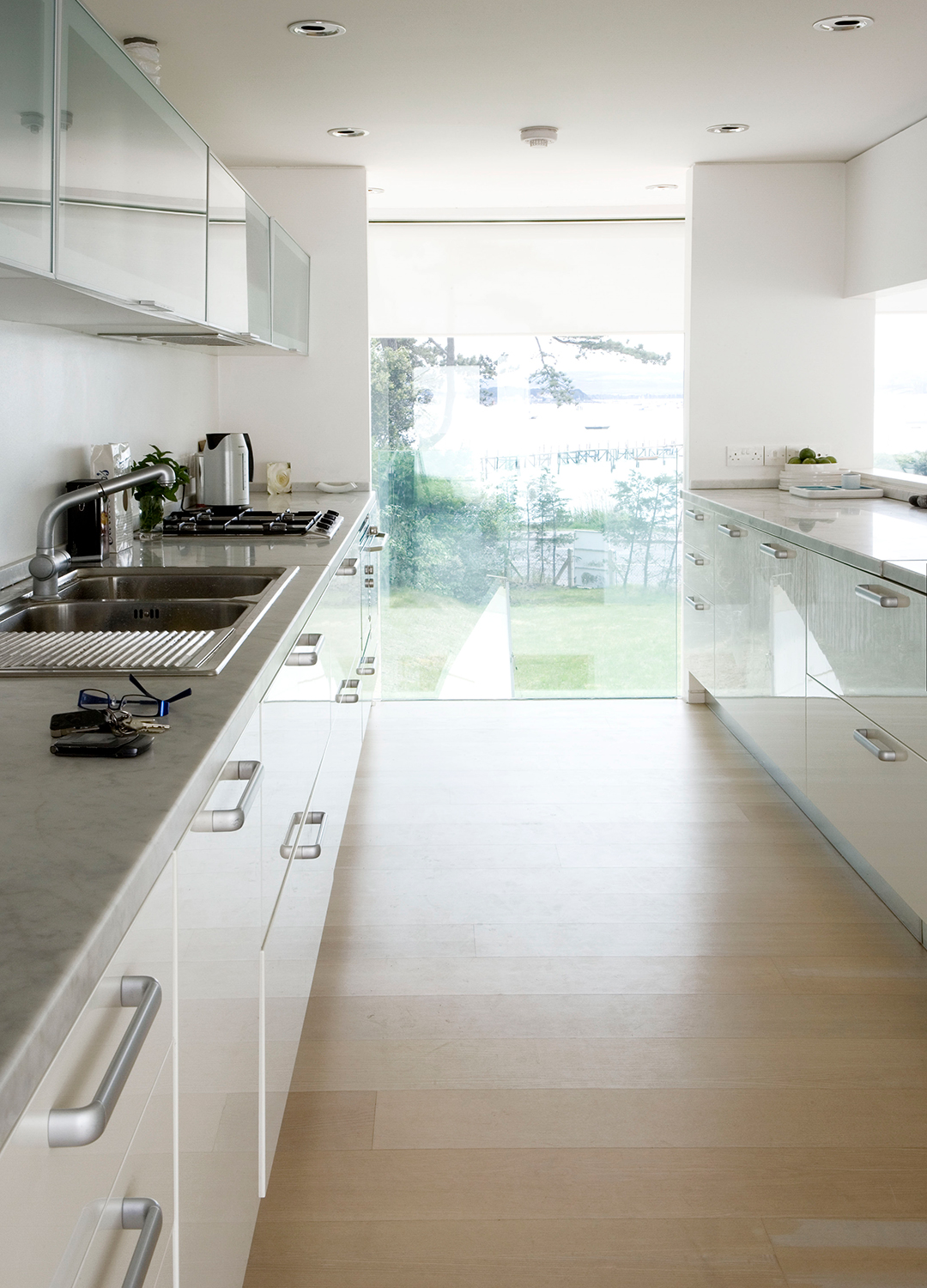 Contemporary white galley kitchen with a window panel out to the garden