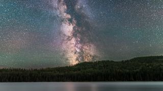 a bright starry sky above a lush green landscape