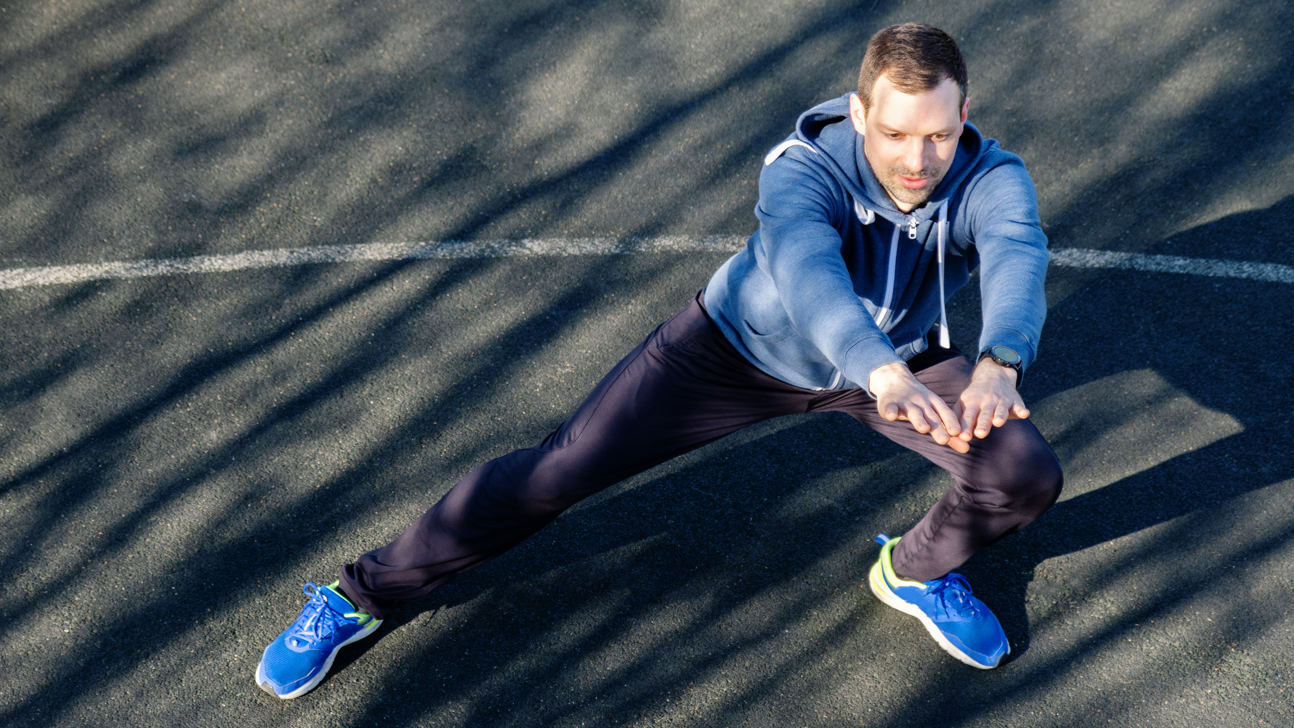 A man performs a side lunge outside in sportswear.