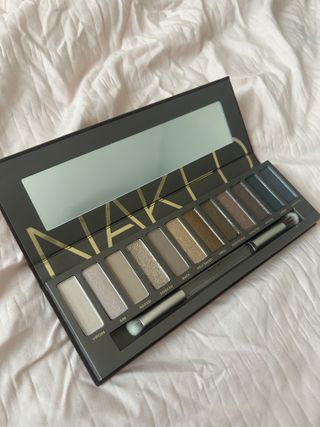 Urban Decay naked neutral eyeshadow palette laying open on light pink fabric background