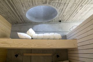 Looking up to a white duvet and pillow on a wood floor at an upper level.