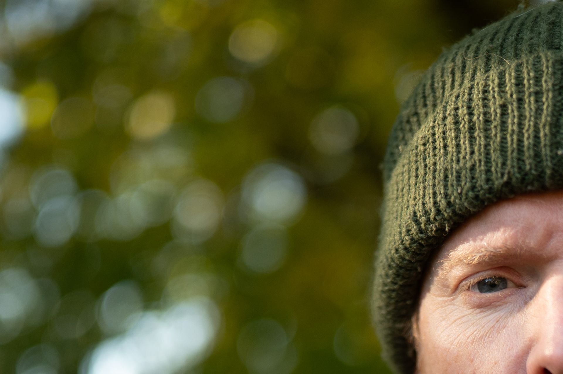 Portrait of a man in a shacket and beanie hat, outdoors with fall trees backdrop