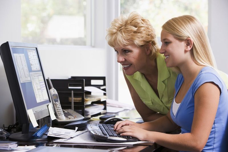 A mother and daughter look at a computer screen together