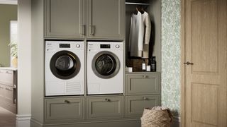 laundry room with green cabinets, appliances and hanging rail