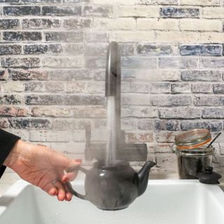 black boiling water tap pouring into black teapot