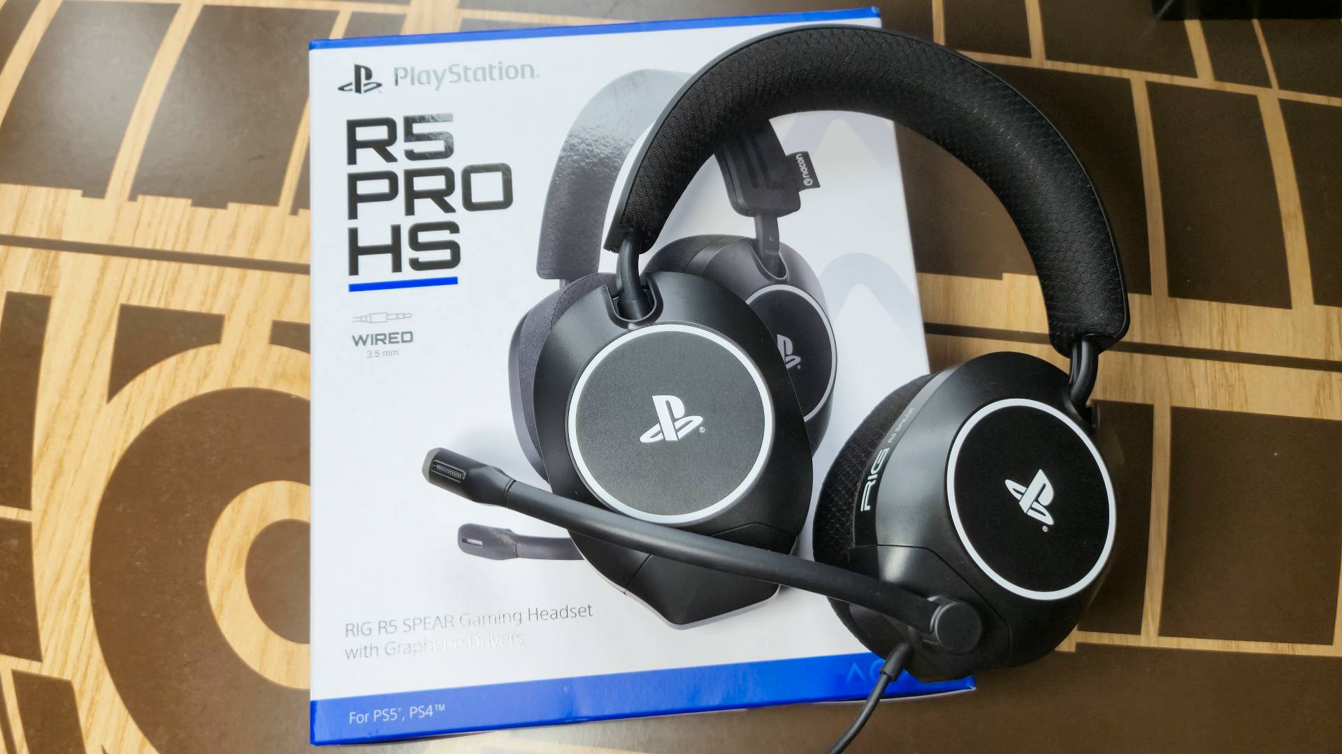 Photo of a black RIG PS5 headset sitting on its white and blue box.