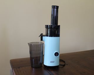 Dash Compact Juicer in Aqua on dark wooden table