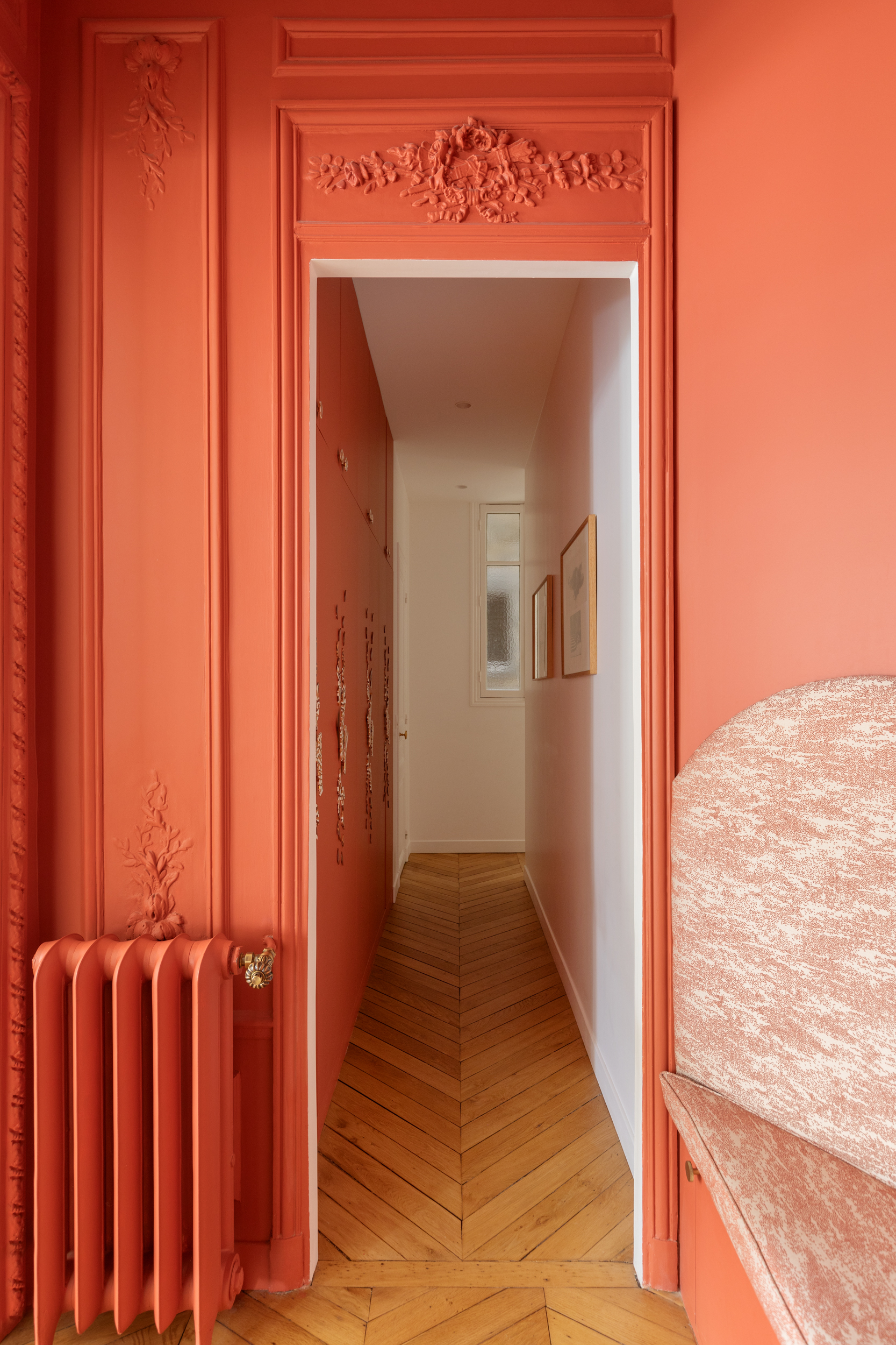 coral orange color drenched hallway in Paris with crown molding