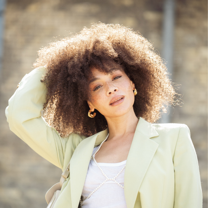Afro haircare brands Julia Dalia wears black pants, white top and mint green blazer