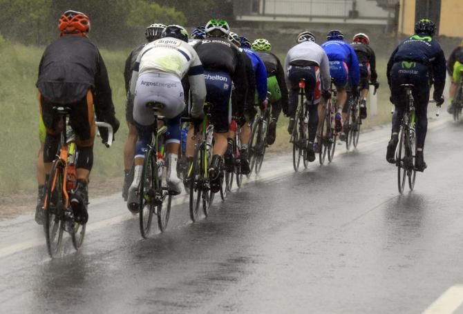 The peloton ride through the wet and cold conditions of stage 14