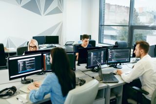 Office workers in a workspace with monitors on desks