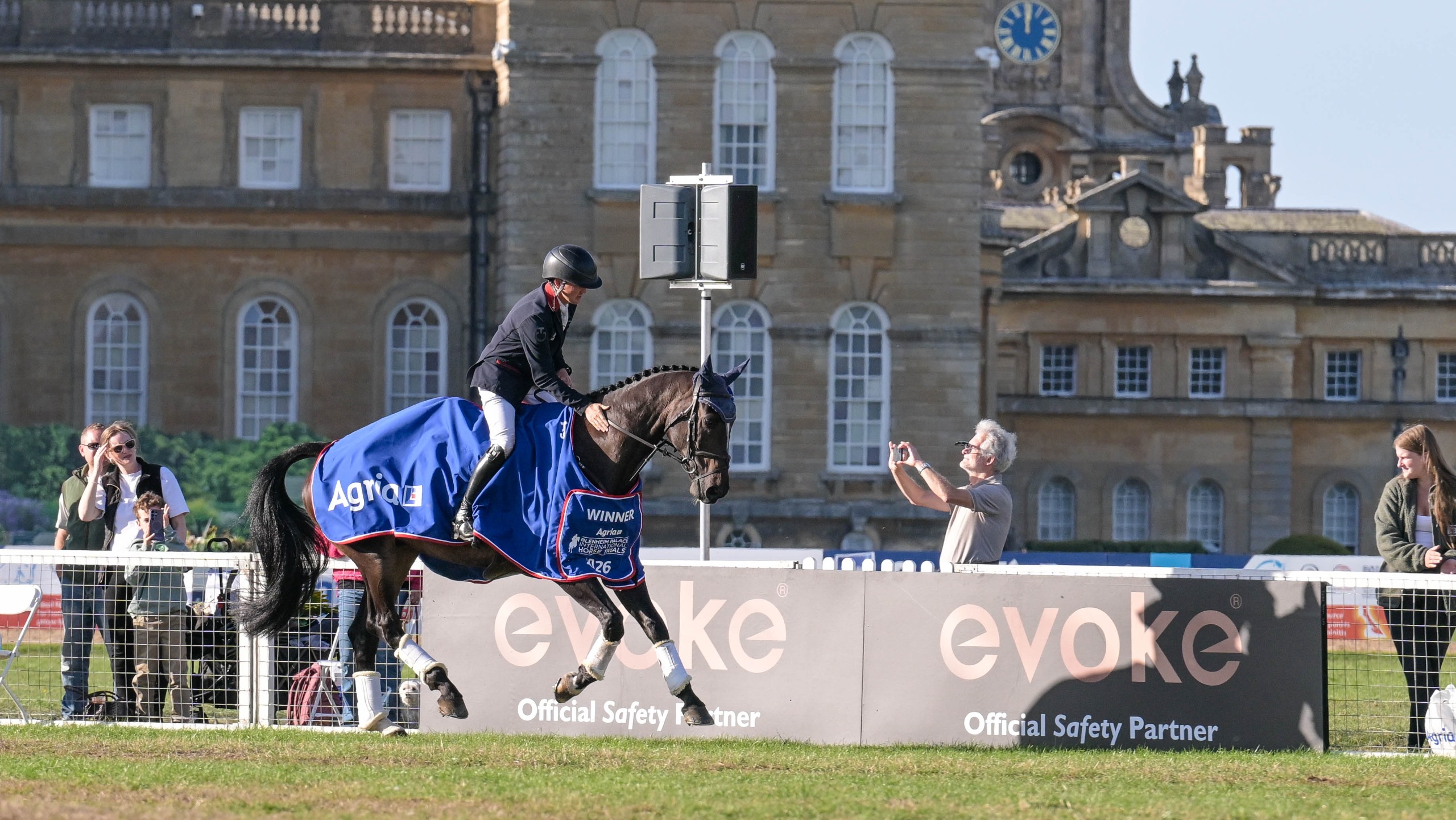 Image shows a Tom McEwen and The Fieldmaster cantering in front of Blenheim Palace on their lap of honour