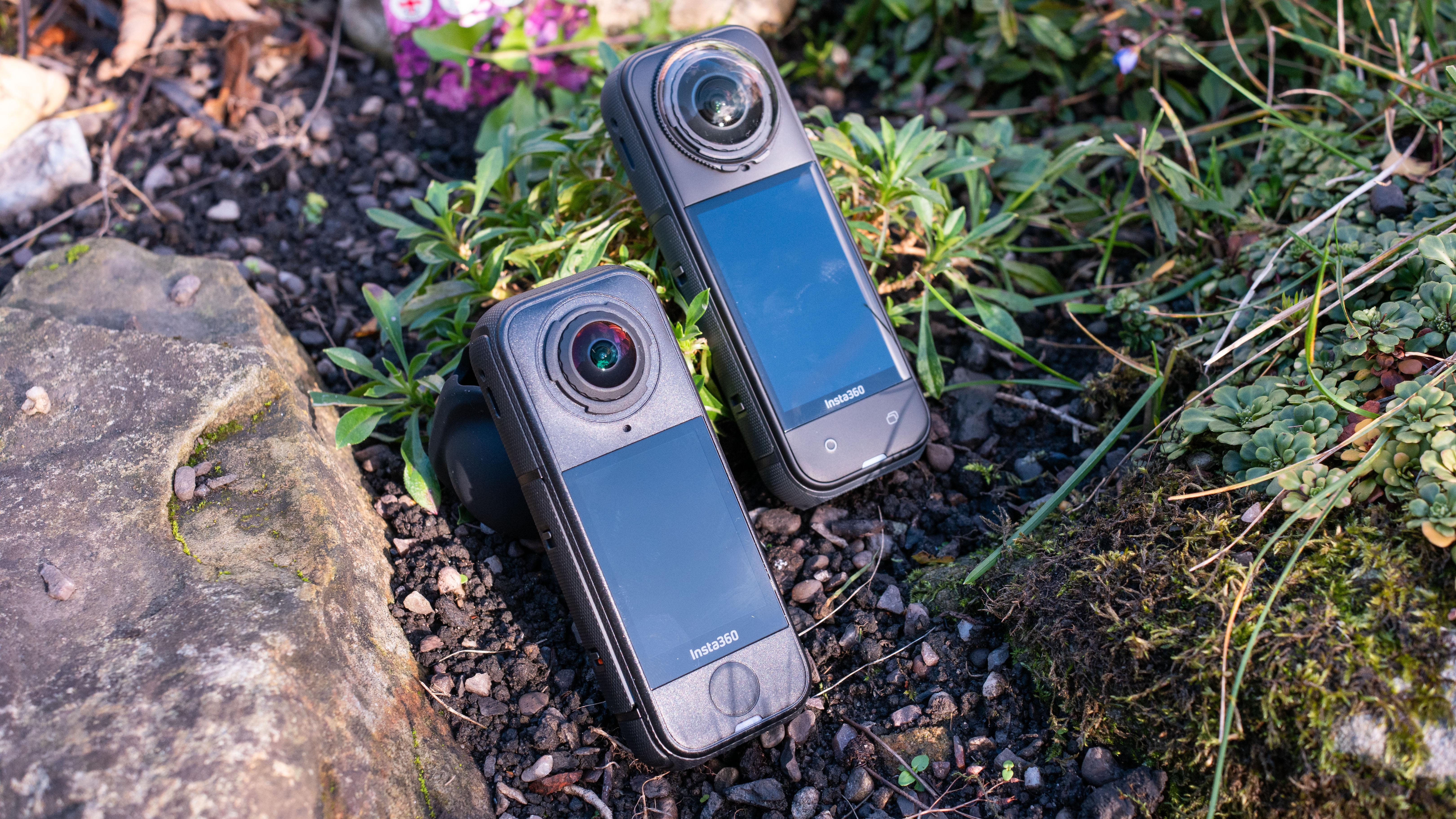 The Insta360 X5 and X4 Air action cameras in an outdoor setting under natural light