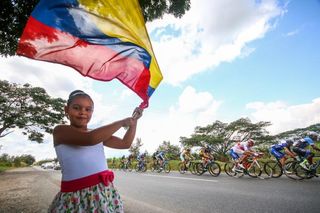 A fan greets the Oro y Paz peloton with the Colombian flag