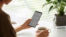 A person holding the TCL 50 Pro Nxtpaper, which displays black text on a plain white background