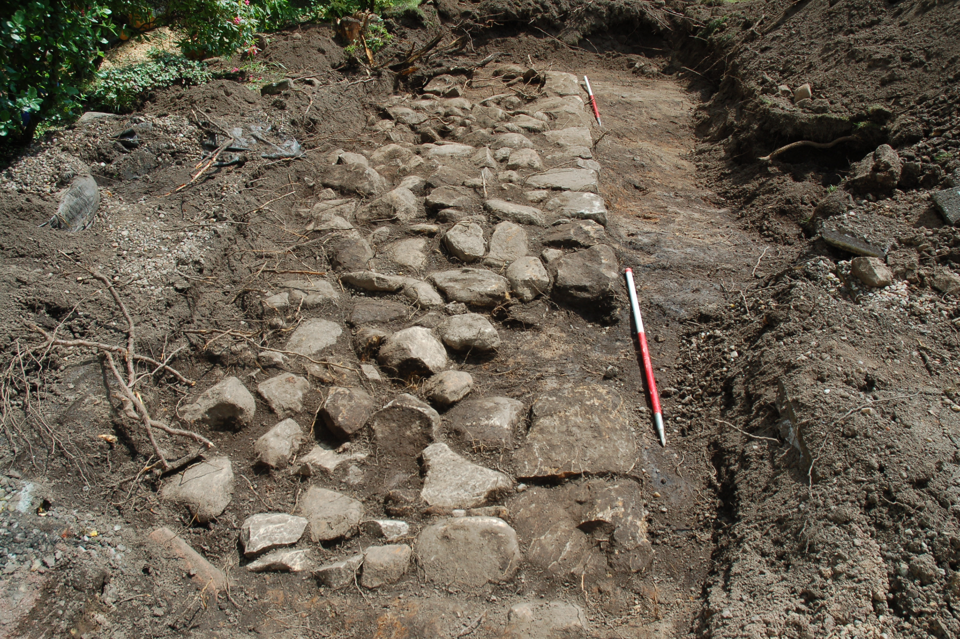 An excavation site showing rectangular stones being unearthed with tools nearby