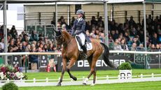 Lizzie Baugh and B Exclusive canter in front of the stands during their Defender Burghley Horse Trials dressage test.