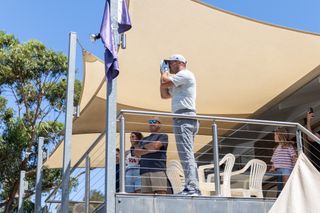 Bryson DeChambeau takes a yardage from a balcony