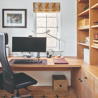 A home office with a built-in desk connected to the storage covering the whole side wall