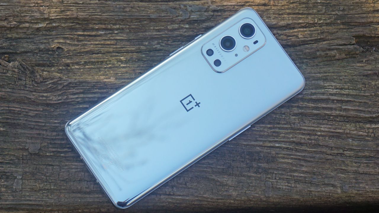 A OnePlus 9 Pro from the back, lying on a wooden surface