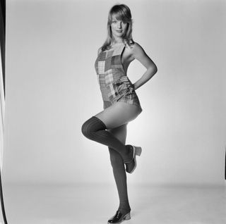 Fashion model Sally Bodington wearing a patched playsuit, over the knee socks and clogs, UK, 19th March 1971.