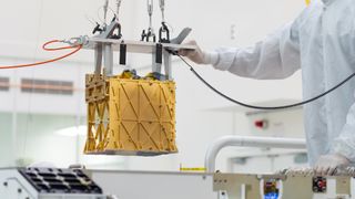 Technicians carefully lower the Mars Oxygen In-Situ Resource Utilization Experiment (MOXIE) instrument into the belly of the Perseverance rover.