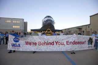 At NASA's Kennedy Space Center in Florida, employees hold up a banner to commemorate space shuttle Endeavour's STS-134 mission as it is moved from its hangar to the Vehicle Assembly Building on Feb. 28, 2011. The shuttle is due to launch its final mission