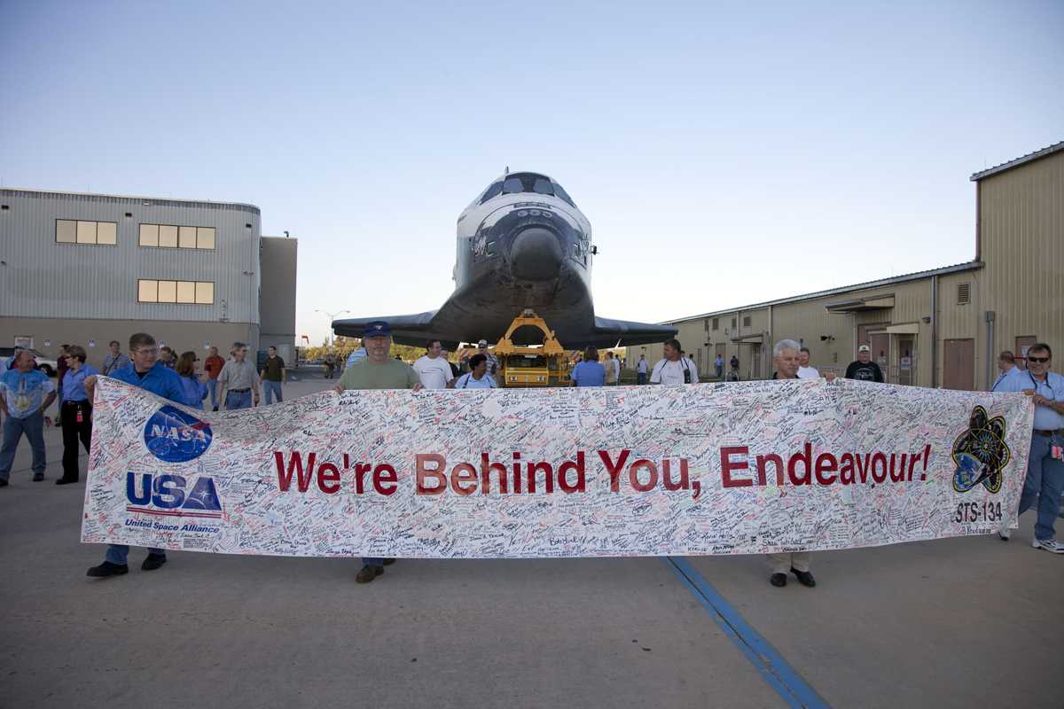 At NASA&#039;s Kennedy Space Center in Florida, employees hold up a banner to commemorate space shuttle Endeavour&#039;s STS-134 mission as it is moved from its hangar to the Vehicle Assembly Building on Feb. 28, 2011. The shuttle is due to launch its final mission