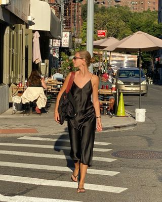 Amalie Moosgaard wearing a black slip dress and black flip-flops