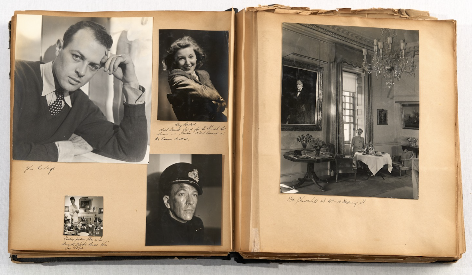 A scrapbook spread with four black-and-white portraits on the left including a relaxed studio shot of a young man and a serious close-up of a figure in naval cap, and on the right a large photograph of a woman seated at a formal dining table in an ornate room with a chandelier and a painted portrait on the wall.