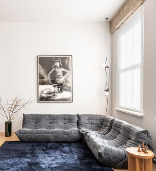 A living room with a gray couch and inky blue carpet