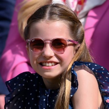 Princess Charlotte wearing a blue polka dot dress and pink sunglasses smiling