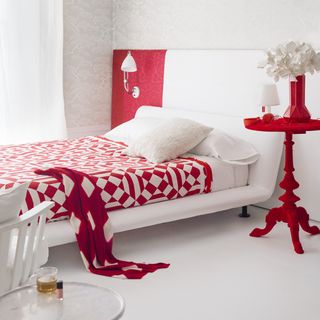 bedroom with white walls and printed red and white bedsheet