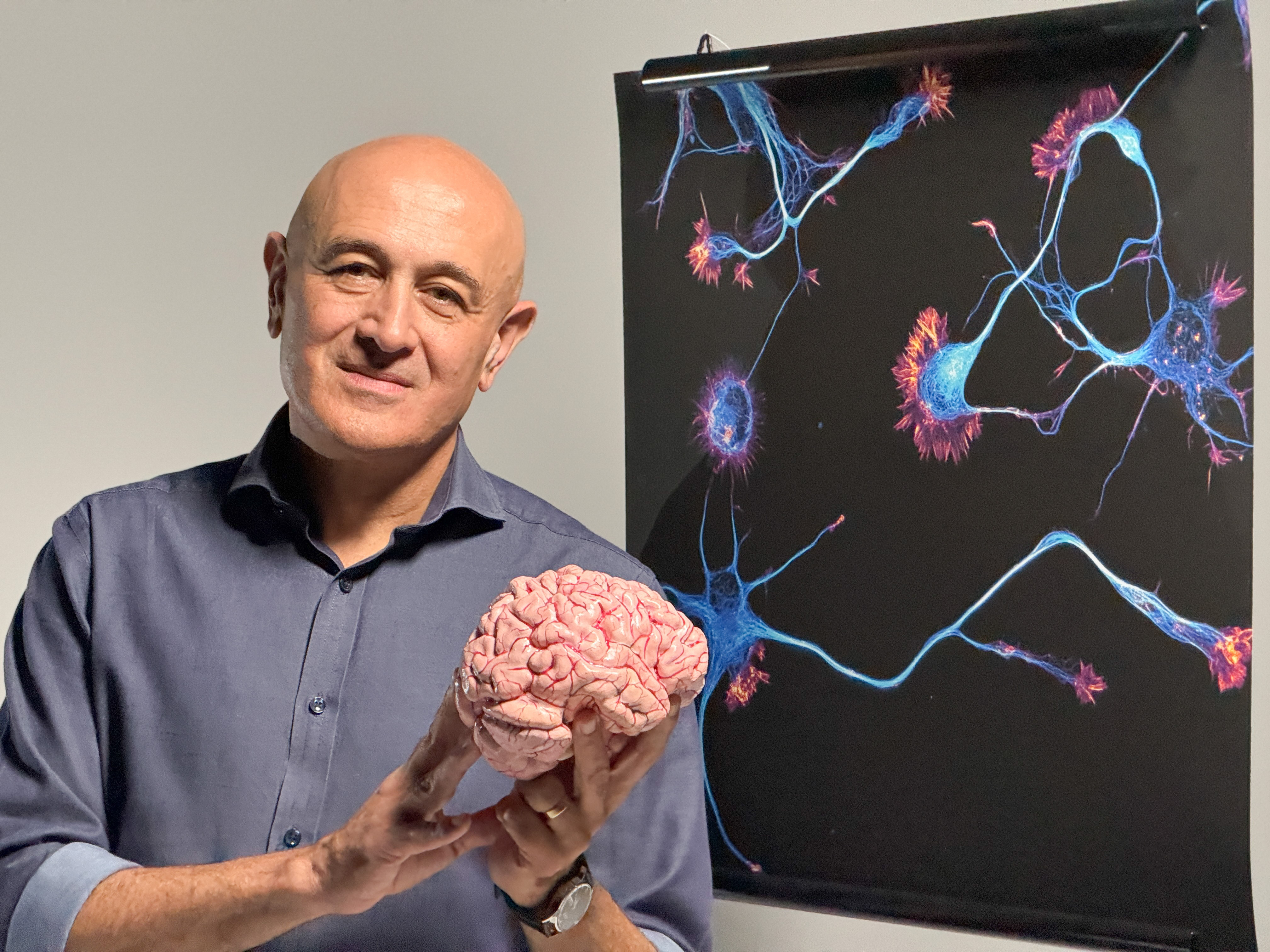 Professor Jim Al-Khalili holding a brain in front of an image of neurons