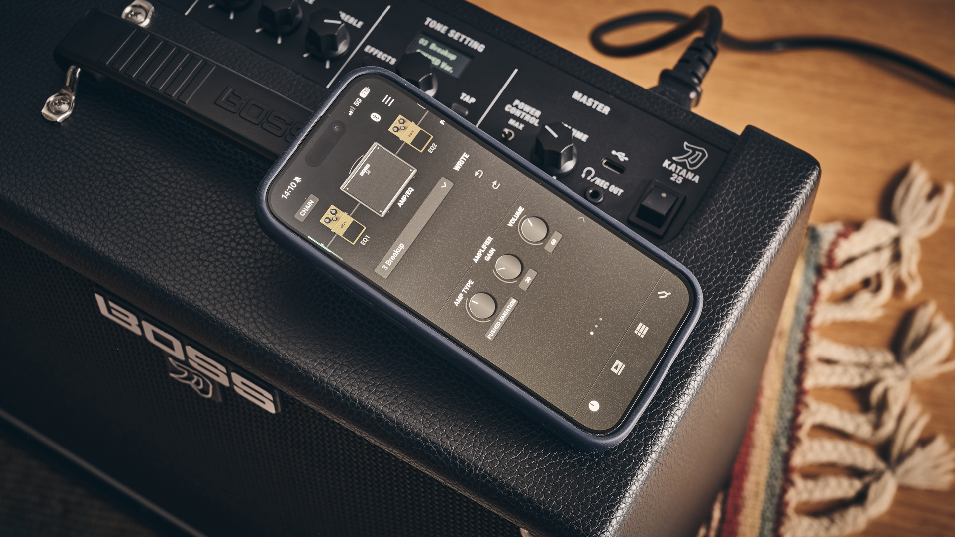 A smartphone running the Boss Tone Studio app on top of the Boss Katana-25