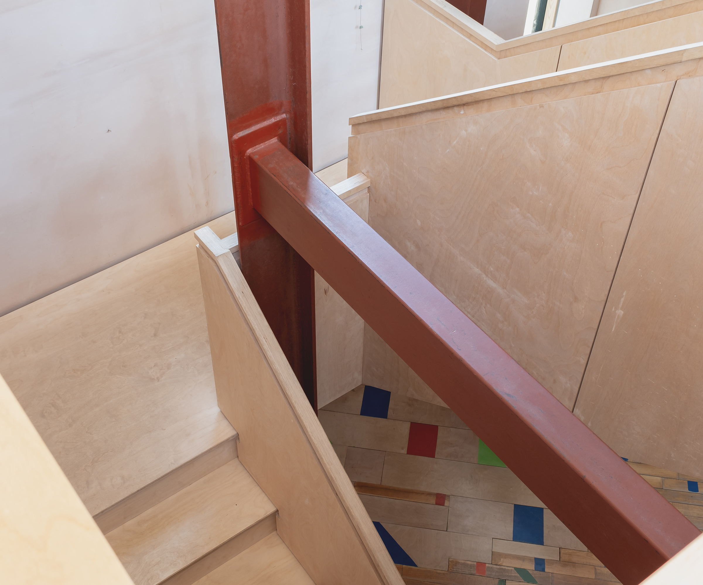 A bespoke staircase in a self build home in natural exposed wood with rust-coloured beams exposed